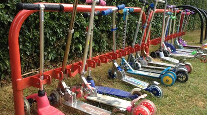 a red scooter rack full of children's scooters in lots of different colours