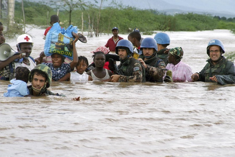 women + children carried across flooded river by blue helmeted UN
