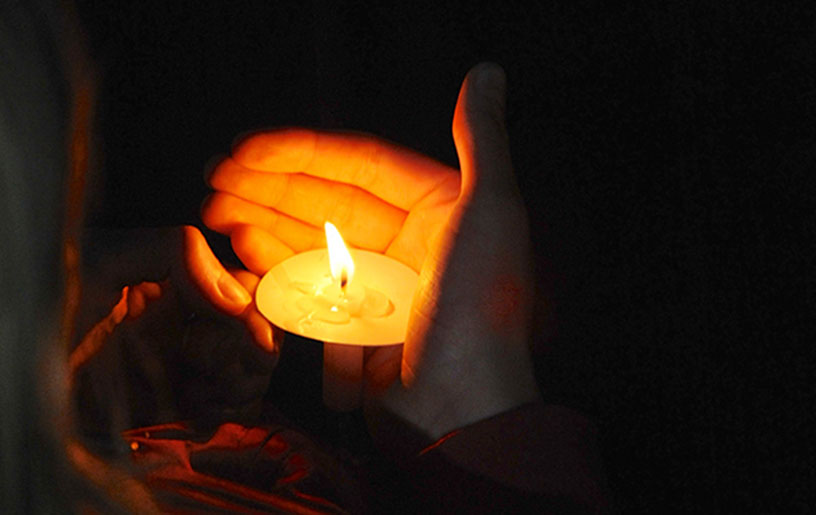 prayerful candle in cupped hands