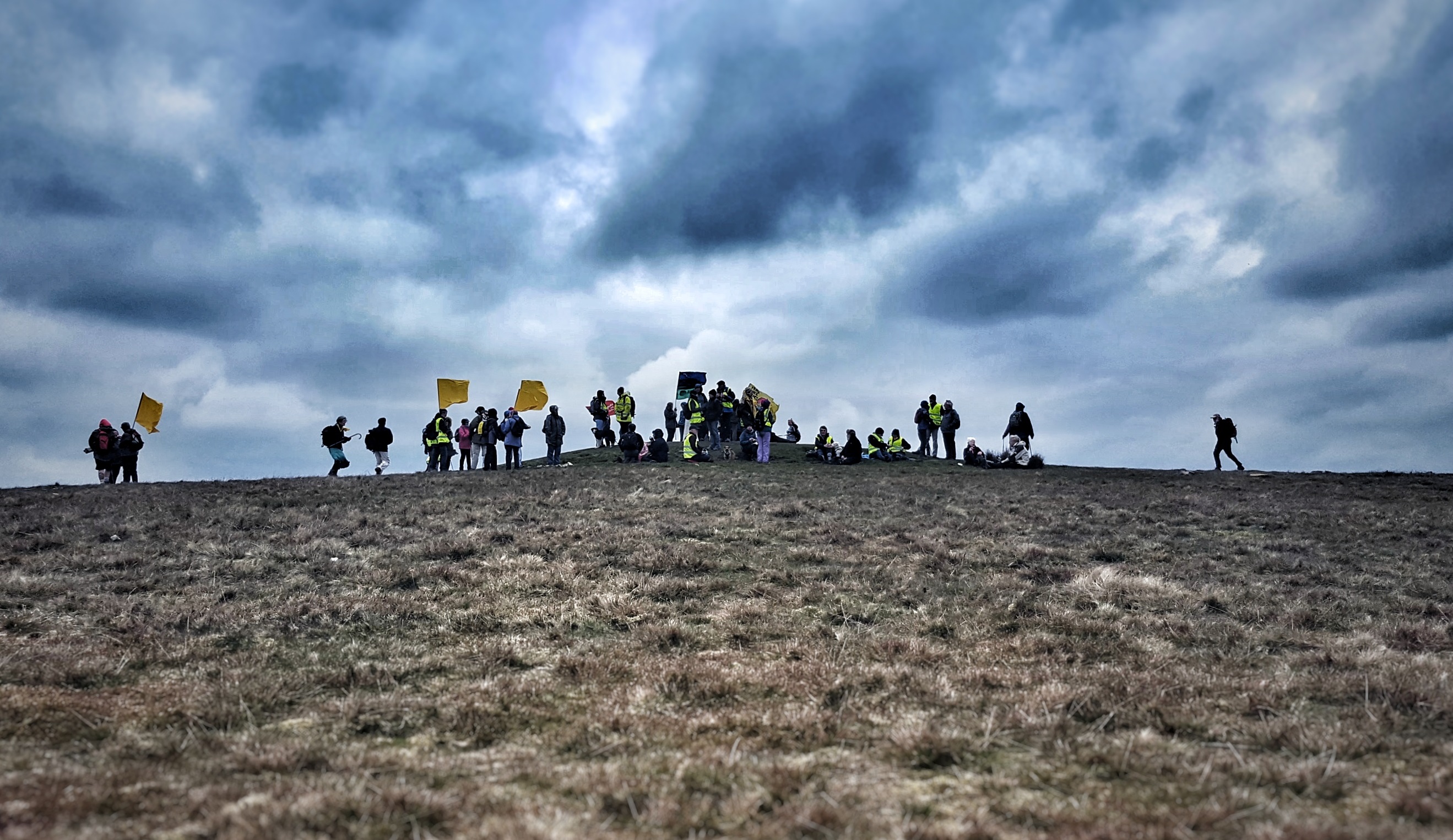 crest of a hill with a dramatic skyline and people gathering at the top