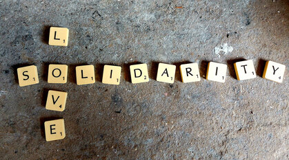 Scrabble letters on concrete spelling out love and solidarity