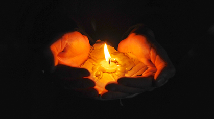 Hands cupped around a candle that has melted wax down into someone's hands