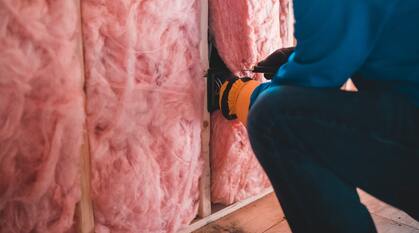 Person fitting a house walls with insulation