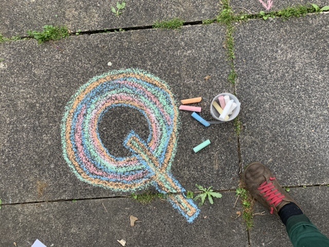 A Q drawn in colourful chalk on the ground