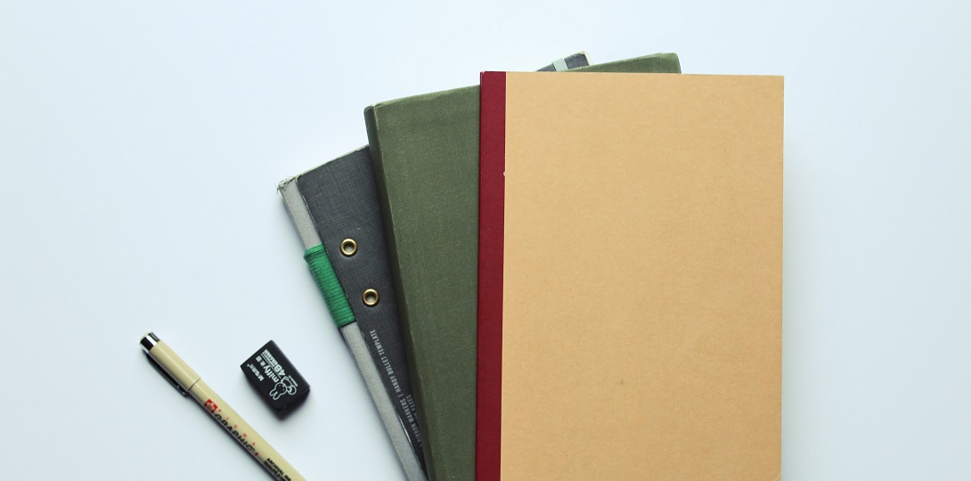 A photograph of a pile of notepads with a pencil and eraser