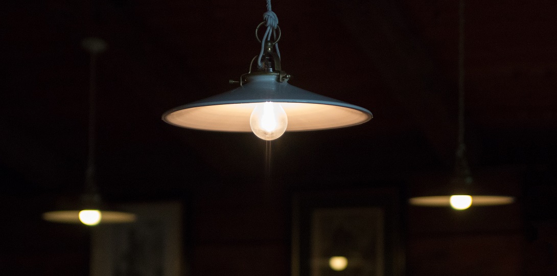 A dark room with three dull light bulbs hanging from the ceiling under lampshades