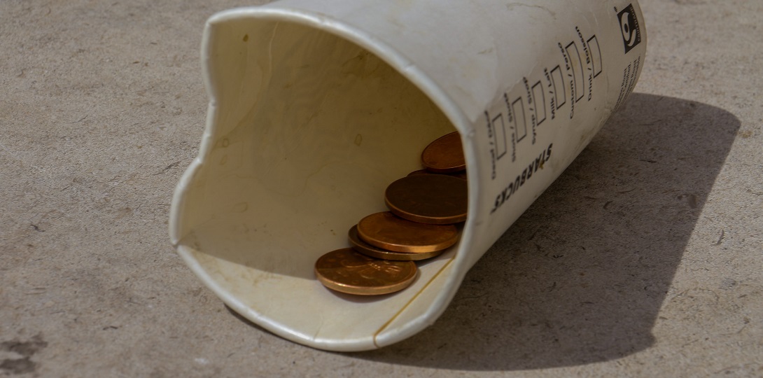 Small change in a paper cup laying on the ground