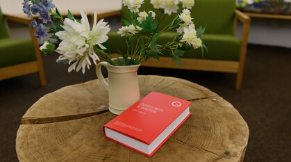 Red book of Quaker faith & practice on a log table with flowers