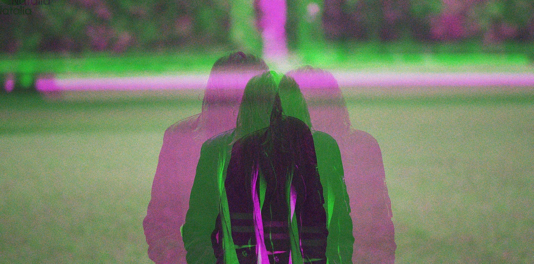 A person walking over grass. The lens captures a doubled up image with the person's outline multiple times
