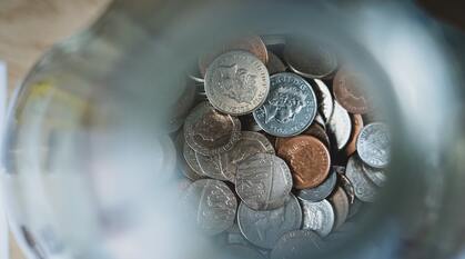 Looking down into a money jar, to see the various sterling coins saved from loose change.