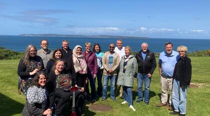 A group of people smiling posing for a photo on a cliff with Rathlin Island in the background