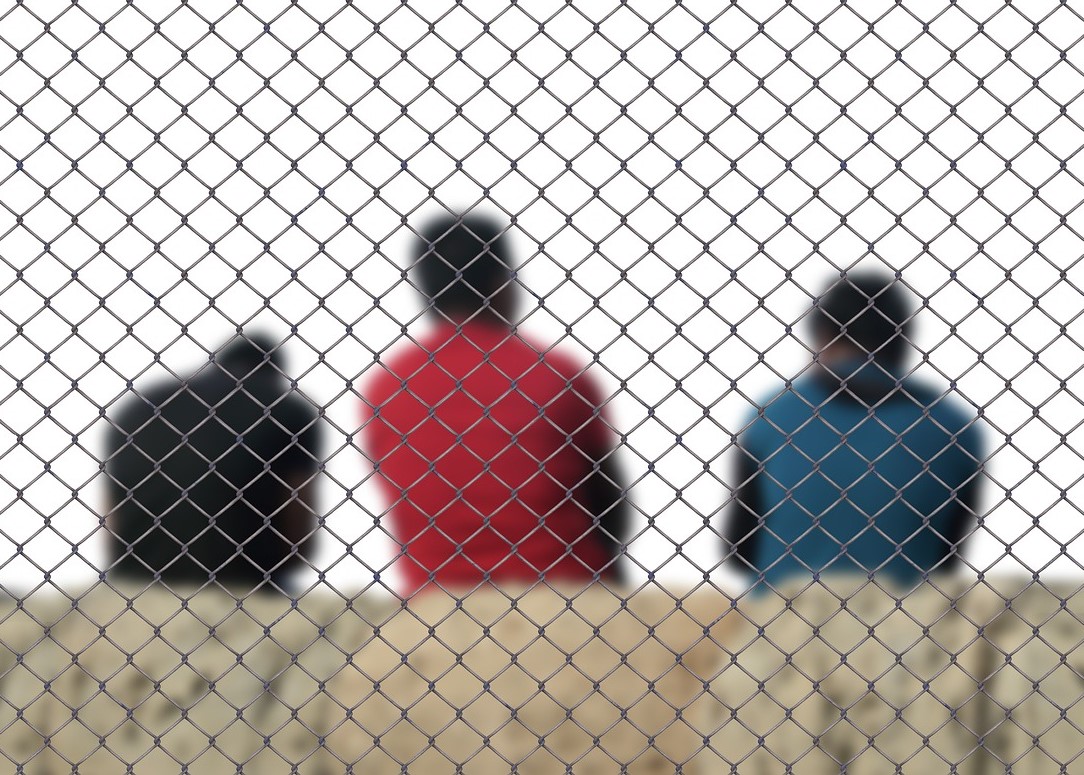 fence in front of three blurred men