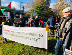 A group of Quakers amongst a wider protest holding a banner saying "use your skills to tackle the climate emergency"