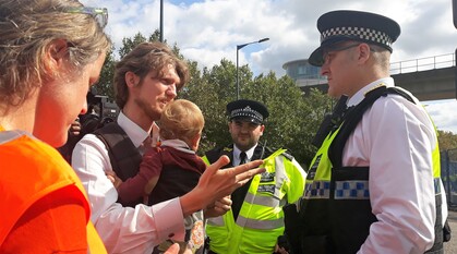 Man with a baby talking to police officers