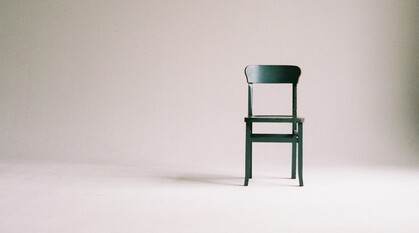 An empty green chair in a white room