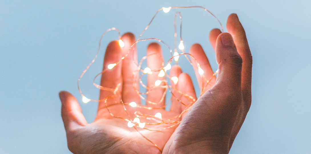 Two hands holding a string of white lights