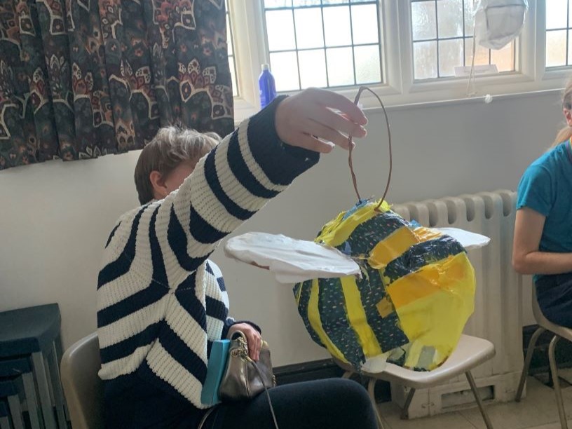 young person in striped jumper holds up stripy bee lantern