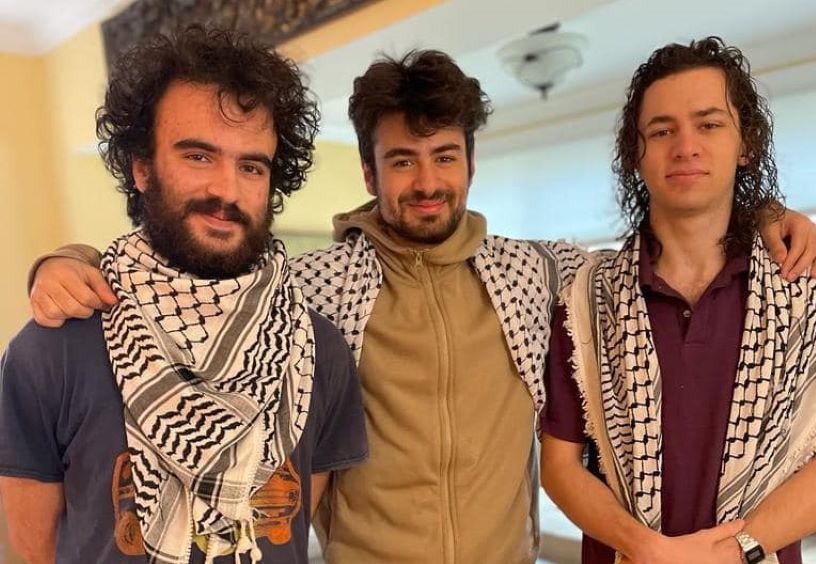 Three young men wearing keffiyeh scarves