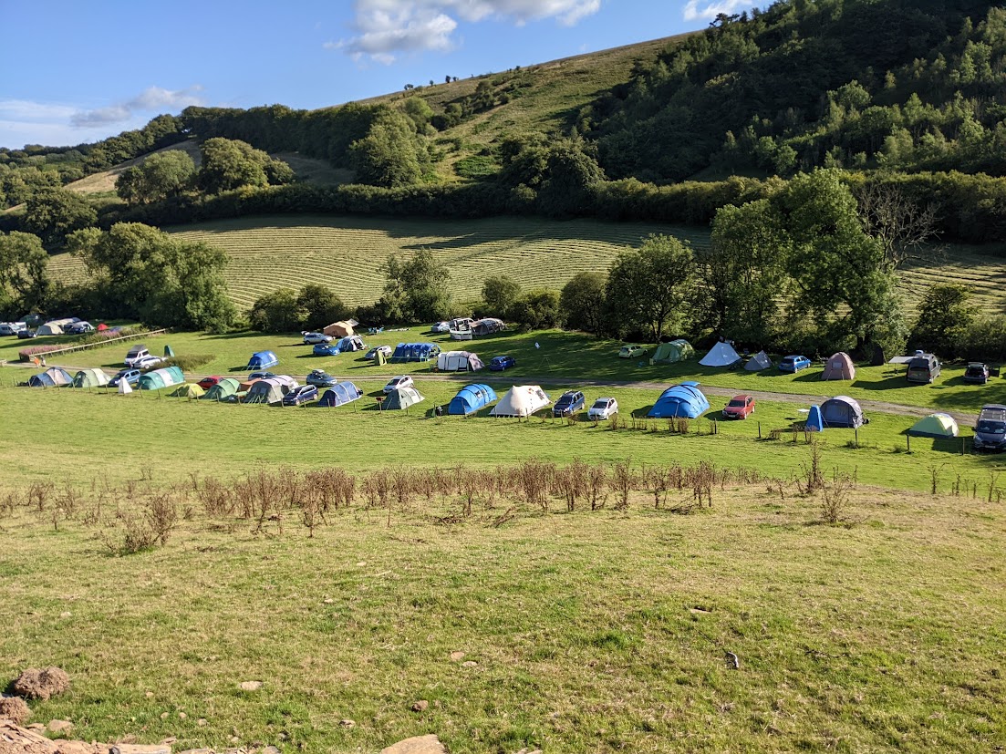 People camping in a green field in the sunshine