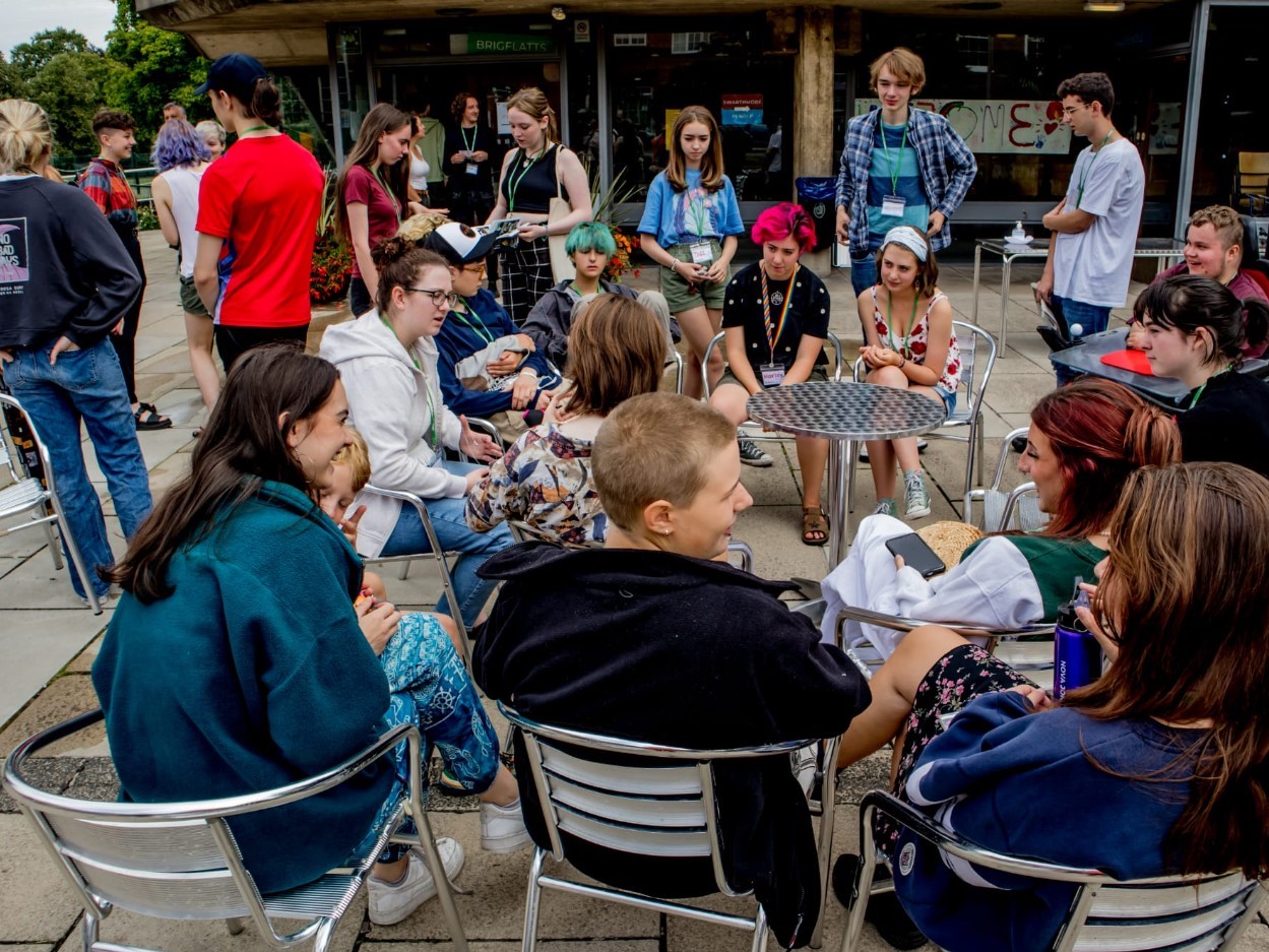 young people sat on cafe chairs in the street