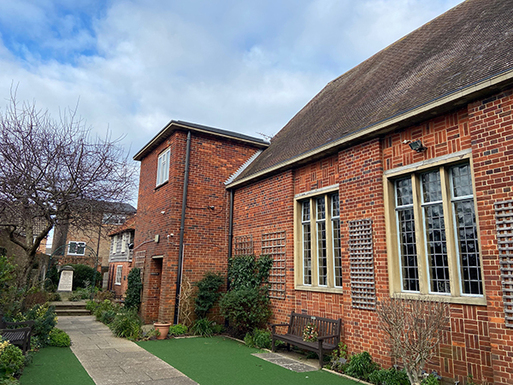 Brick building with straight paved path and some leaded windows