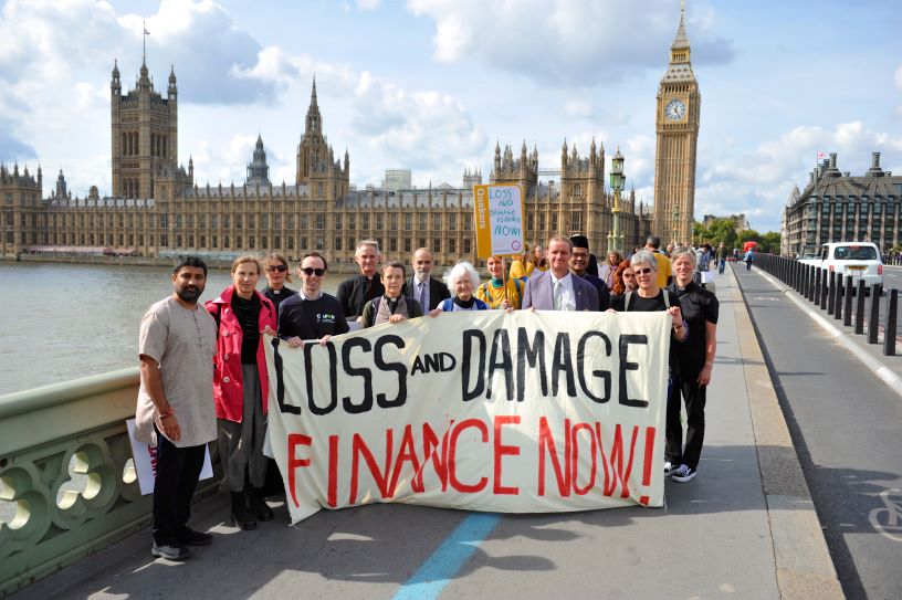 People with banner in front of Parliament