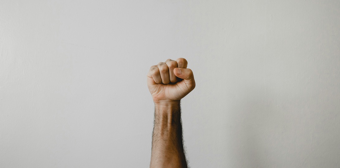 The fist of a man of colour raised against a pale background