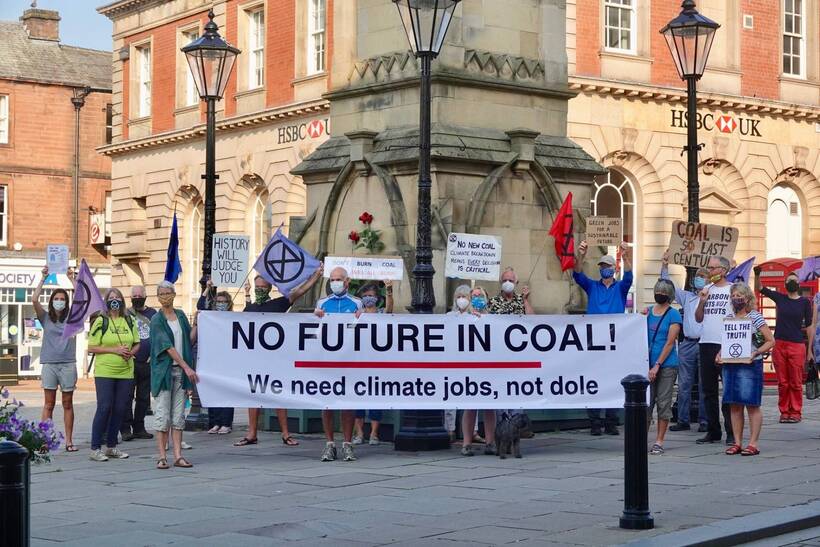People standing in a town centre holding a banner which reads: " Nofuture in coal! We need climate jobs, not dole"