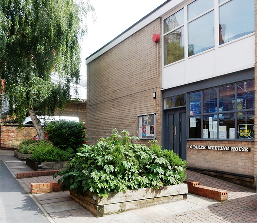 Modern flat roof building of grey brick with a birch tree to the side..