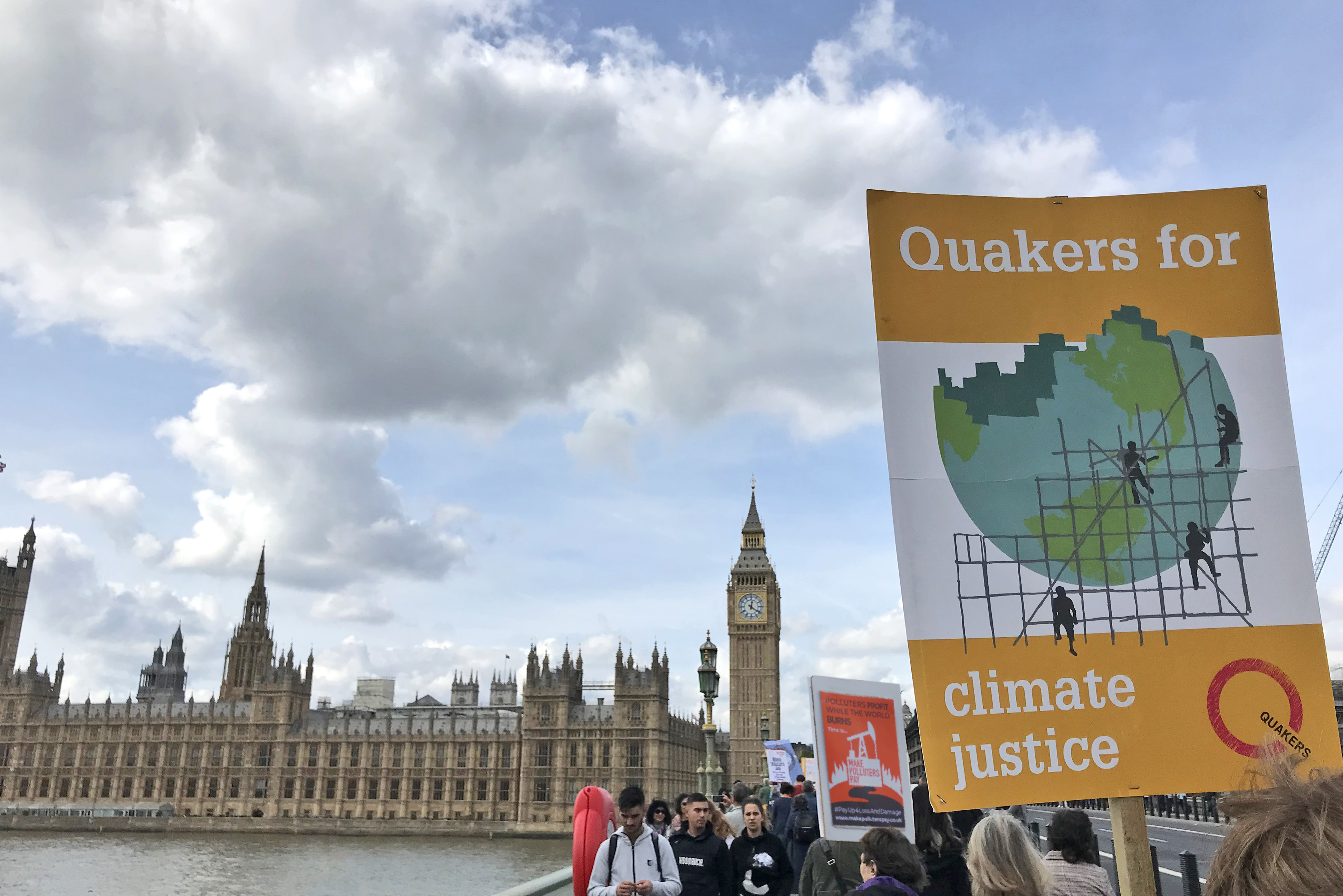 A placard that says "Quakers for Climate Justice" with Parliament in the background