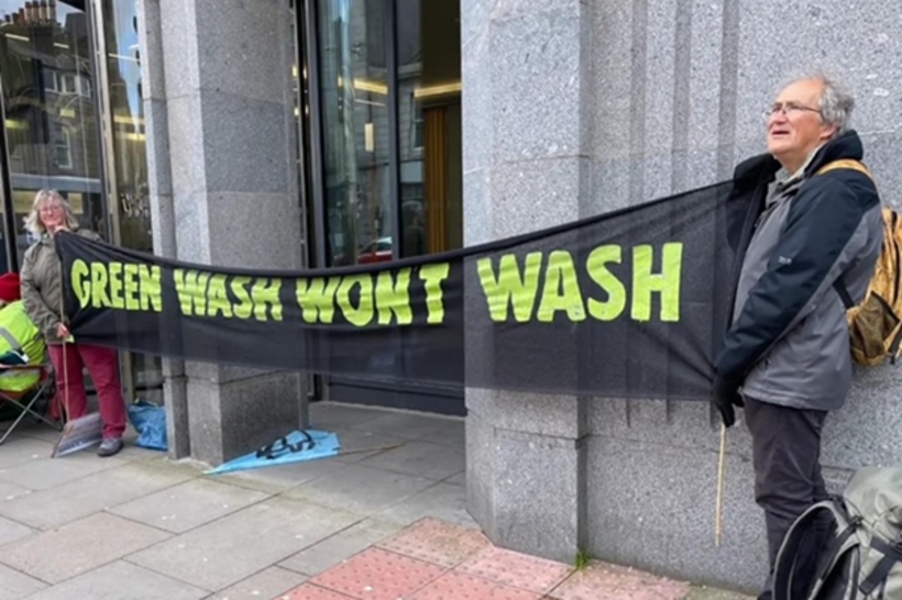 Two Quakers hold a "Greenwash won't wash" banner outside Shell's offices in the Silver Fin Building in Aberdeen