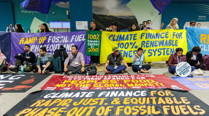 Groups of people holding banners calling for climate finance, and a phase out of fossil fuels