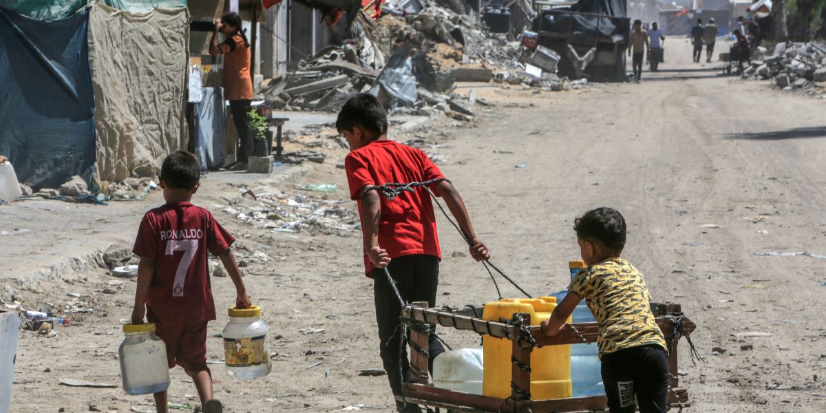 Three children pulling a water trolley