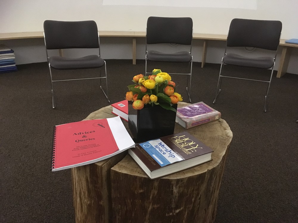 Table set up with bible, Quaker advices and queries and flowers, chairs in background