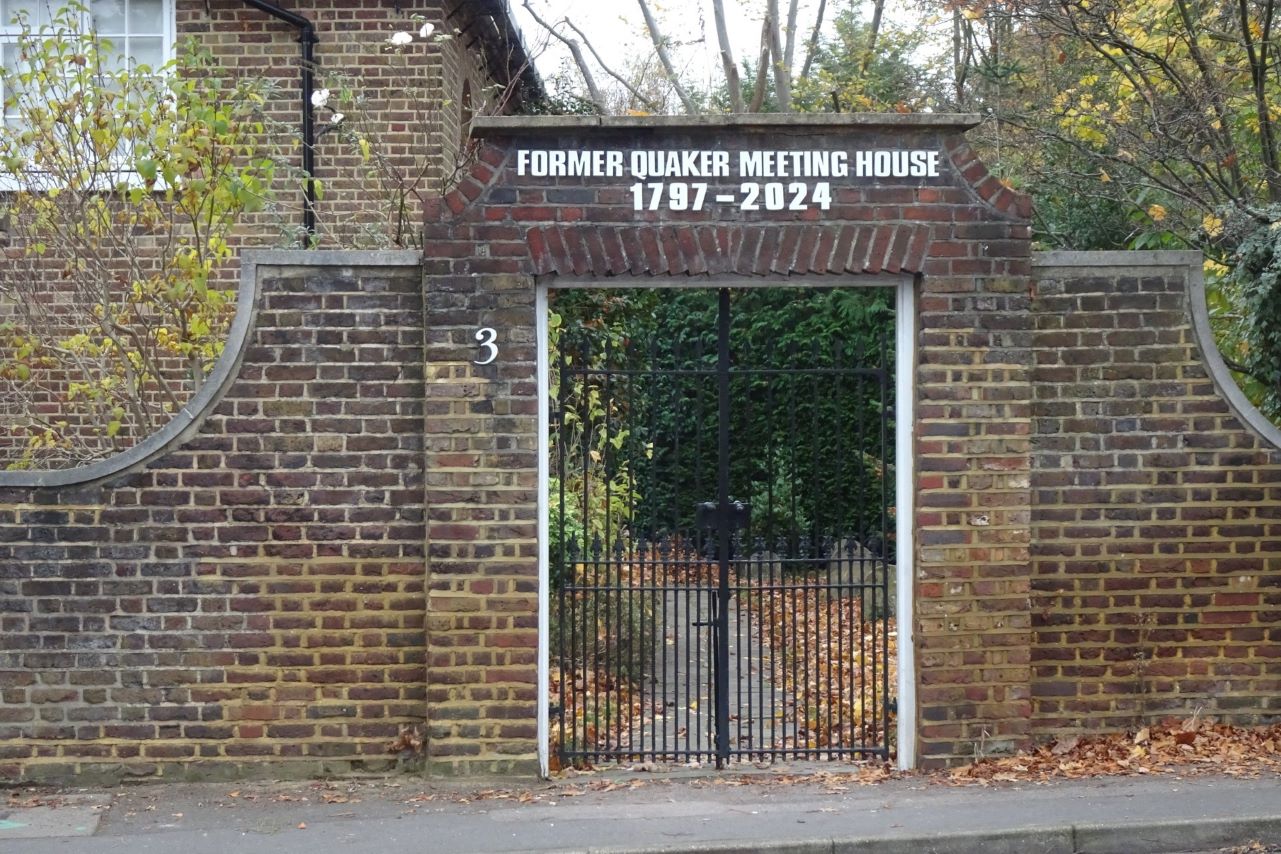 red brick wall and black gate with lettering 