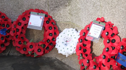 Three poppy wreaths rest against a stone background - two red ones and a smaller white one.