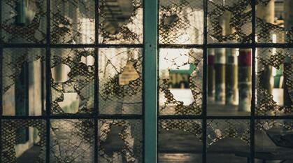 An image of a broken window, behind the window a prison ward is visible