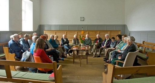 Group of people in a circle in an old room with seventeenth century furniture