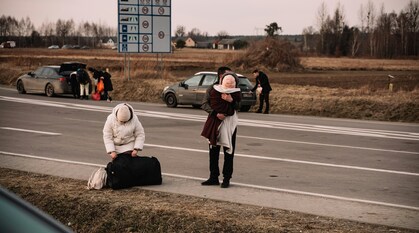 A family stands on the side of the road, preparing to flee Ukraine.