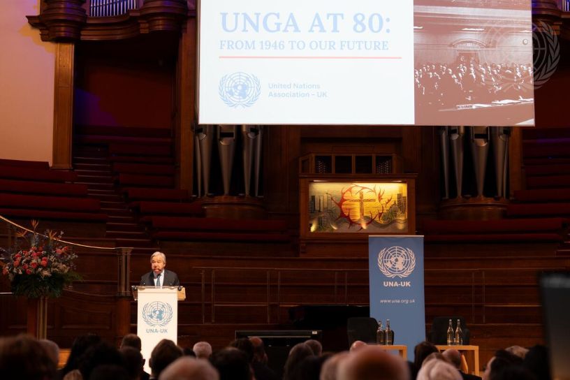 Man at a lectern in front of large banner