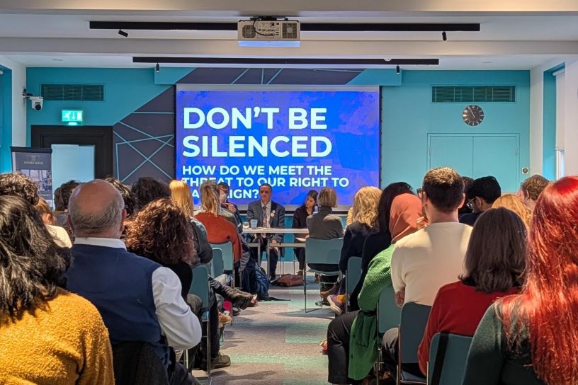 Audience and panel under slide reading Don't Be Silenced