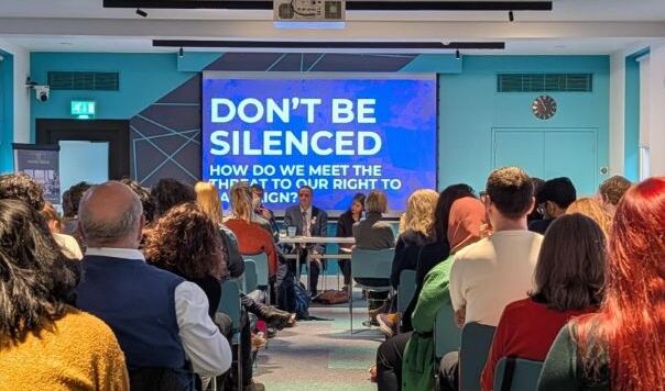 Panel and audience in front of slide reading Don't be silenced