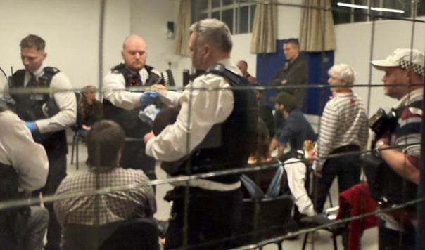 policemen in a room with seated peopole