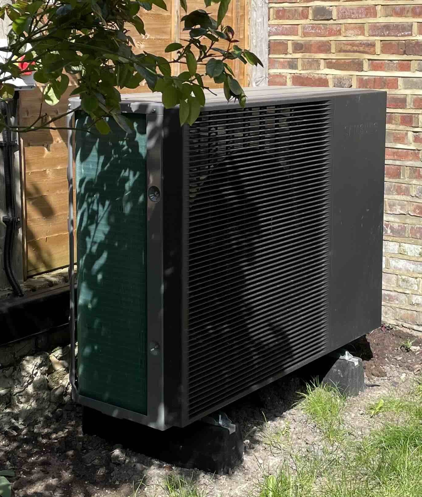 Black heat pump outside a UK home on a sunny day