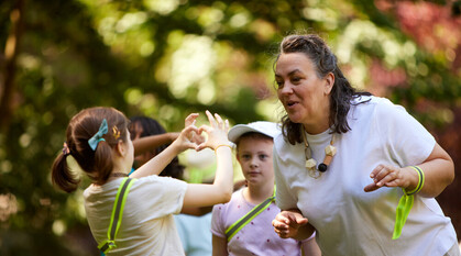 a child shows an adult how to make a heart with two hands