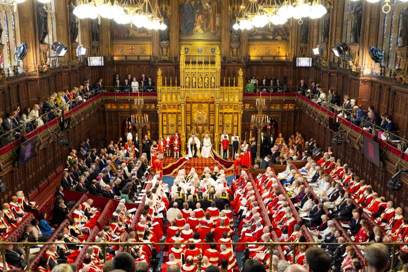 Ornate chamber full of people in red coats