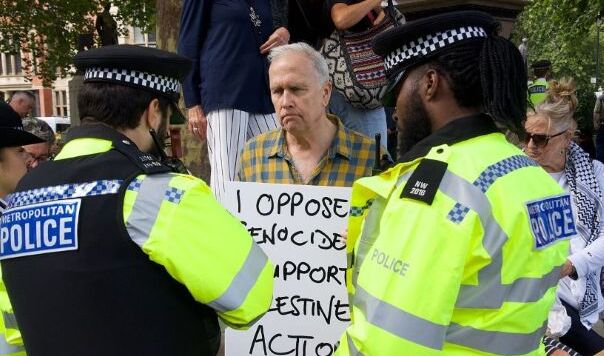 Man with placard behind two policemen