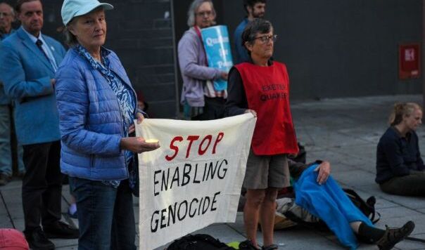 Two people holding a banner saying Stop Enabling Genocide