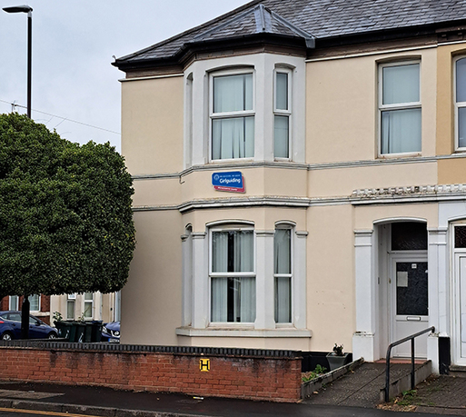 Two storey, cream-colour painted house with bay windows and a slate roof